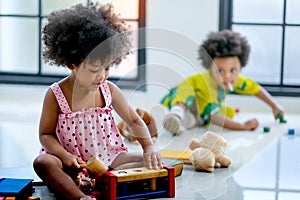 One African mixed race girl is playing with toys in front of the other boy and look enjoy and happy with this activity