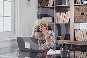One alone unhappy and sad woman at home in the office using laptop and looking at it with hands in the head. Stressed female in