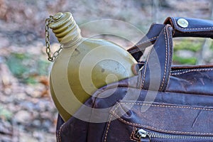 one aluminum closed old army flask lies in a brown leather backpack pocket