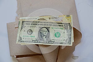 One American dollar and one hundred Ukrainian hryvnia lie on toilet paper on a white background close up