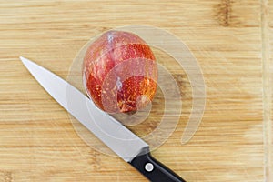 One Amigo Pluots on a Wood Chopping Board with a Knife