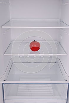 One apple in open empty refrigerator.