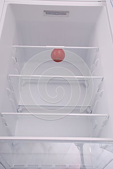 One apple in open empty refrigerator.