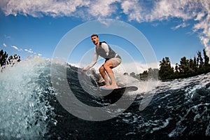 one-armed man wakesurfing on the board down the wave against the background of sky