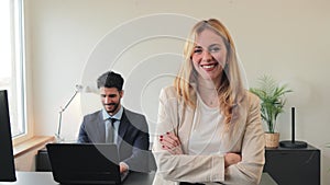 One arms crossed businesswoman smiling and looking at camera standing at corporate office. Clerk female staring front