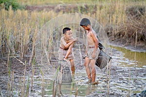 One Asian boy point or action look like play with his friend during catch fish in rice field with evening light