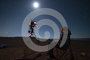 One astronomer man looking the night sky through an amateur telescope and taking photos to the Christmas Star rising over the