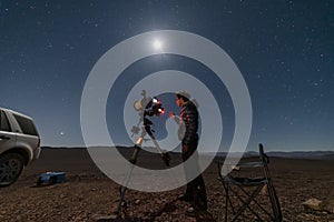 One astronomer man looking the night sky through an amateur telescope and taking photos to the Christmas Star rising over the