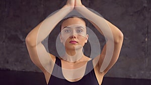 One attractive 20s female person sitting in lotus position on matting and breathing inside of yogas studio closeup