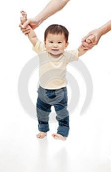 One baby is learning walking isolated on white, the child girl looks at camera and smiling