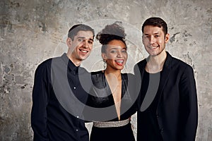 One beautiful african american woman standing with two handsome men, smiling. Elegant style. Studio background.