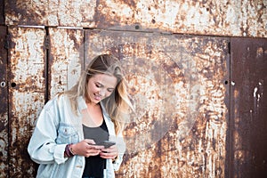 One beautiful and blonde woman in a urban zone using her phone smiling - online and social network lifestyle and concept