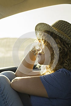 one, beautiful curly woman enjoying her vacations outdoors traveling with a car - sunset and sunny day