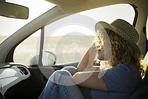 One, beautiful curly woman enjoying her vacations outdoors traveling with a car - sunset and sunny day at the background - relaxed