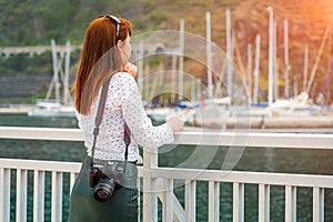 One beautiful readhead girl with camera look at the marina in the sunshine. Woman ready to shoot travel photo on Canary