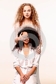 One girl closes the other`s eyes. Afro and Blond