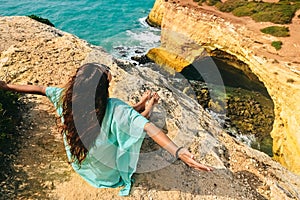 One beautiful sexy girl sits on stones on a rock in Portugal. back view of the ocean