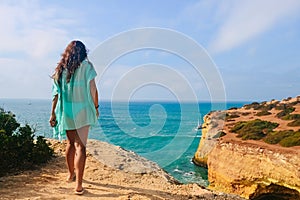 One beautiful sexy girl stands on stones on a rock in Portugal. back view of the ocean