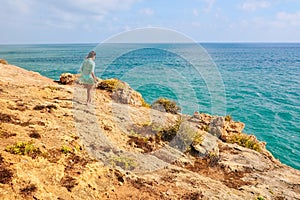 One beautiful sexy girl stands on stones on a rock in Portugal. back view of the ocean