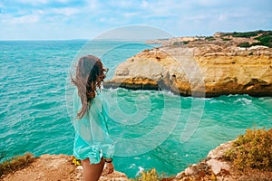 One beautiful sexy girl stands on stones on a rock in Portugal. back view of the ocean