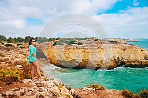 One beautiful sexy girl stands on stones on a rock in Portugal. ocean view, girl looking at the camera