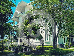 One beautiful three-story house with palm trees, trees, and landscape design in the summer.
