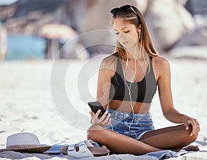 One beautiful young caucasian woman relaxing and listening to music while sitting on the beach. Enjoying a summer