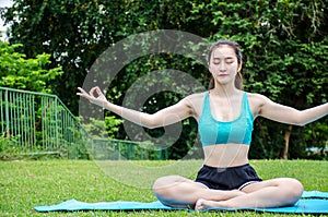 One beautiful young woman sit meditation doing yoga in park. Relaxing and meditating while being surrounded by nature in summer