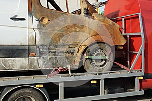 One big burnt car a minibus stands on a tow truck