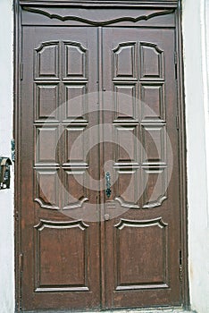 One big closed old brown wooden door on a concrete wall