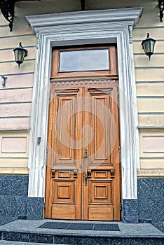 One big closed old brown wooden door on a concrete wall