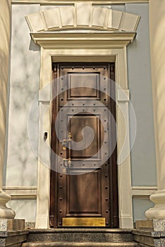 one big closed old brown wooden door on a white gray concrete wall