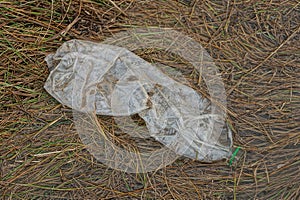 One big dirty white plastic bottle lies on brown grass