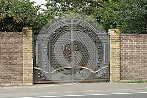 One big gray black metal gate with an iron wrought iron pattern and sharp rods