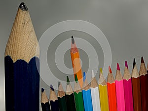 One Big Scruffy Pencil, Standing Alongside a Small Group of Smart Sharp Coloured Pencils.