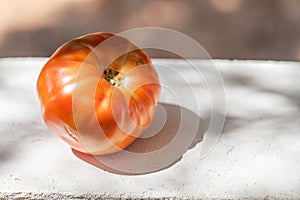One big tomato on the concrete wall on the blurred natural background, copy space