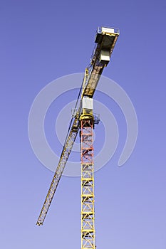 One big yellow construction cranes on blue sky background