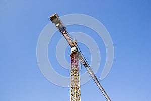 One big yellow construction cranes on blue sky background