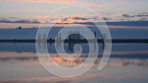 One bird flies over water during sunrise