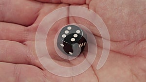 One black dice with number six to gambling in craps in human hand