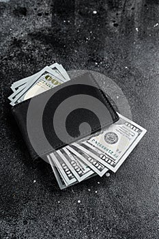 One black purse with the big pack of dollars, Cash of dollar note. Black background. Top view. Copy space