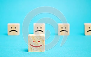 One block with a positive face stands out from the rest of the negative emotions. Concept of good rating, review and feedback.