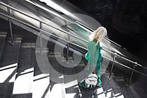 One blonde woman in green outfit walking down the subway stairs