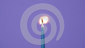 One blue cake candle burning on a purple background. Close up on burning cake candle. Full HD resolution slow motion