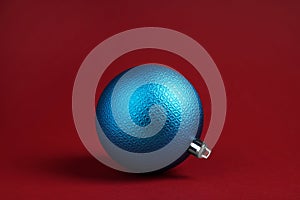 One blue Christmas ball on red background