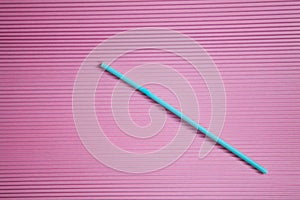 One blue drinking straw on a pink background, without a plastic Cup. Colorful summer background with Sunny shadows and a copy of