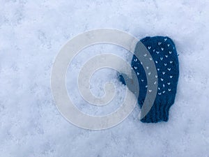 One blue knitted heart pattern baby child glove on snow background isolated