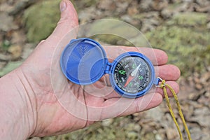 one blue plastic compass lies on an open palm on the hand