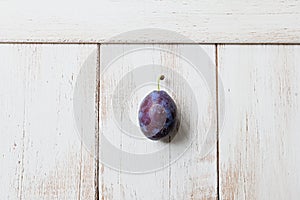 One blue plum on white background