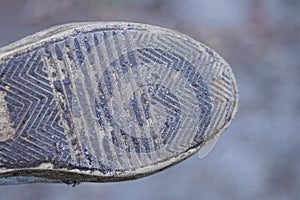 one boot with a rubber dirty old sole with a brown gray pattern